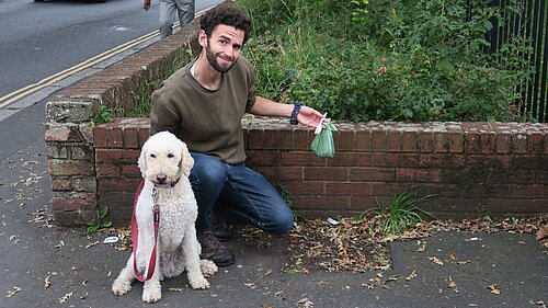 Will Aczel with dog, Ayla, holds up some rubbish by a former bin site on Old Tiverton Rd, Exeter.